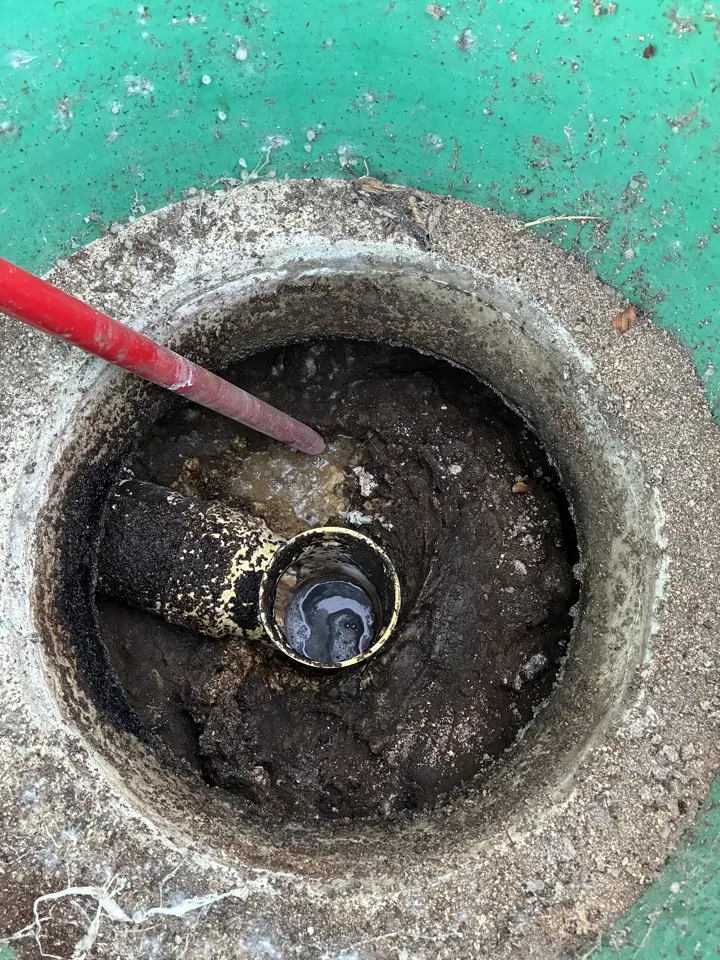 Looking down through a riser into a septic tank at the outlet tee