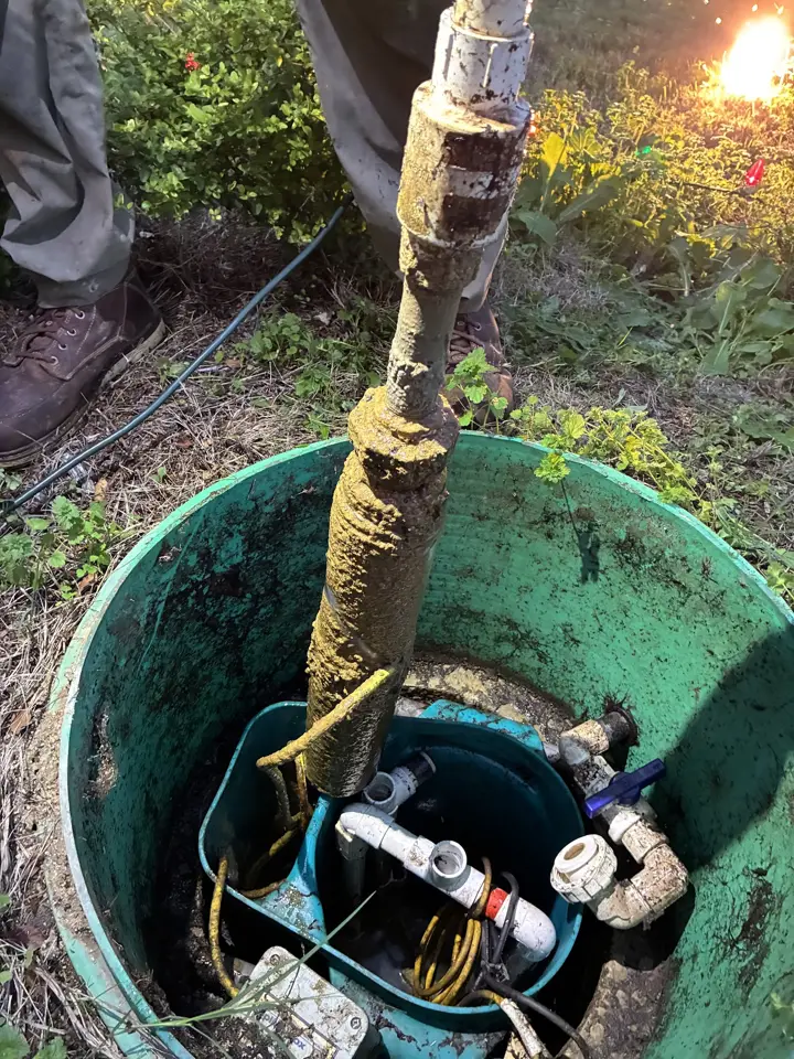 Open green riser on a septic pump tank, showing the pump, float and discharge plumbing inside